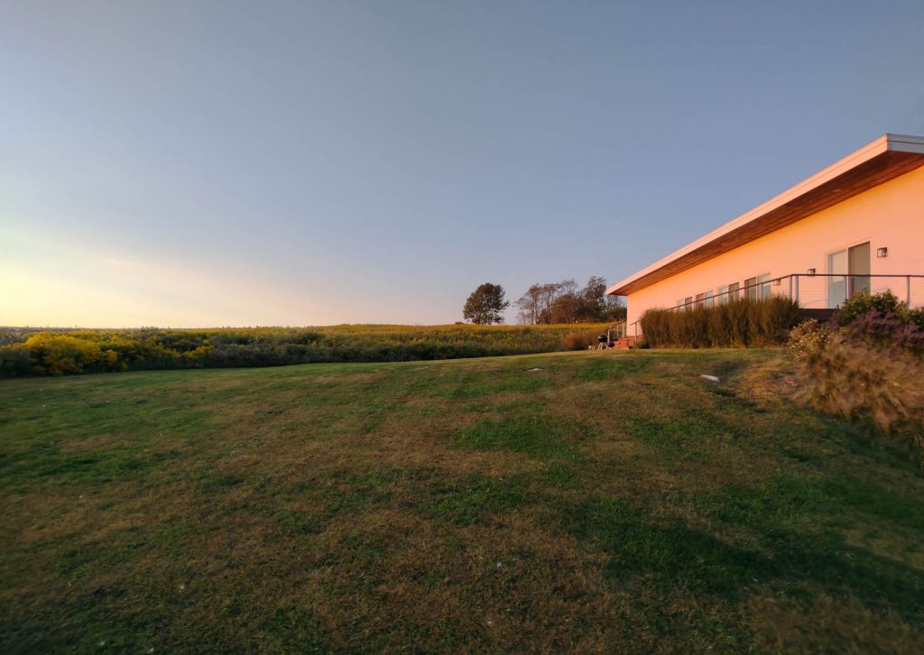 The exterior of a house as the sun meets the horizon.